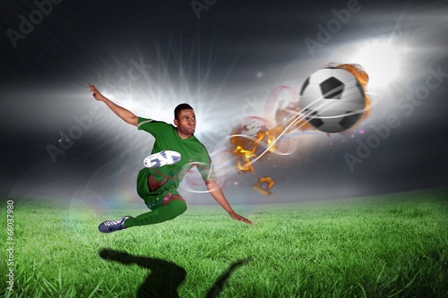 Fototapeta Composite image of football player in green kicking