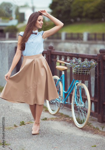 Young beautiful, elegantly dressed woman with bicycle