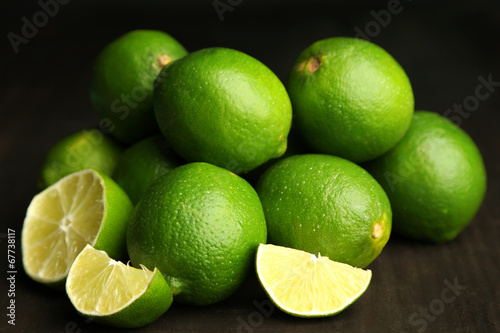 Fresh juicy limes on wooden table, on dark background