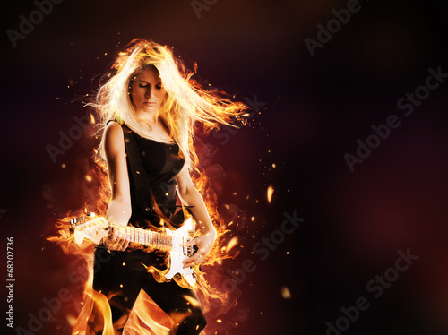 Fototapeta Young woman in flames playing on guitar