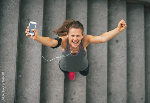 Zdjęcia Portrait of happy fitness young woman with cell phone