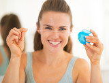 Closeup on happy young woman showing <b>dental floss</b> - 160_F_72269190_mnJBXJeTqi6K5ERx0mRwYoAkdRM0DWHp