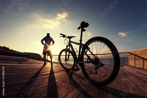  silhouette of sportsman and his mountain bike at the sunset