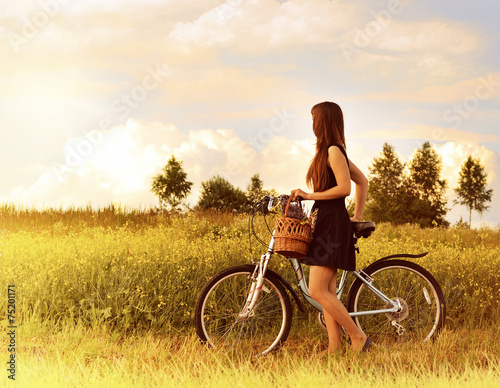 Fototapeta beautiful girl riding bicycle in a grass field