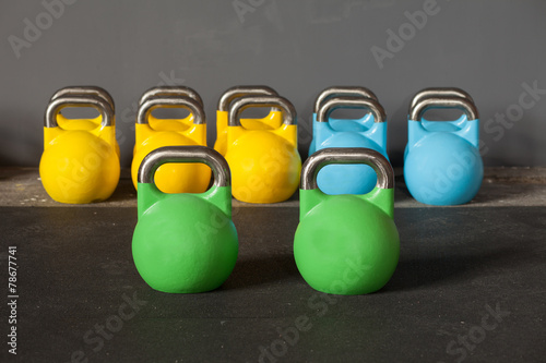 Zdjęcia colorful kettlebells in a row in a gym - focus on the front kett