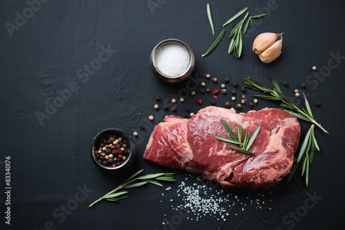 Zdjęcia Above view of raw ribeye steak with spices over black background