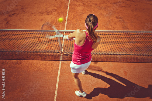 Obraz na plátně Young woman playing tennis.High angle view.Backhand volley.
