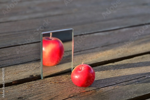 Little Apple is reflected in the mirror. But the reflection looks like the big Apple