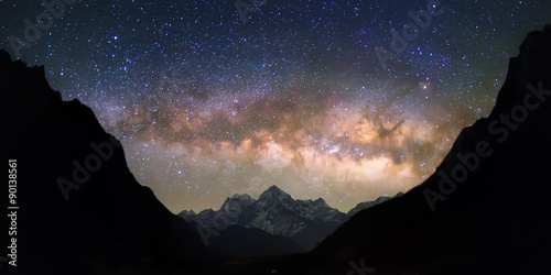 Bowl of Heavens. Bright and vivid Milky Way galaxy over the snowy mountains. Beautiful starry night sky seems to be in a "bowl" between the silhouetted hills.