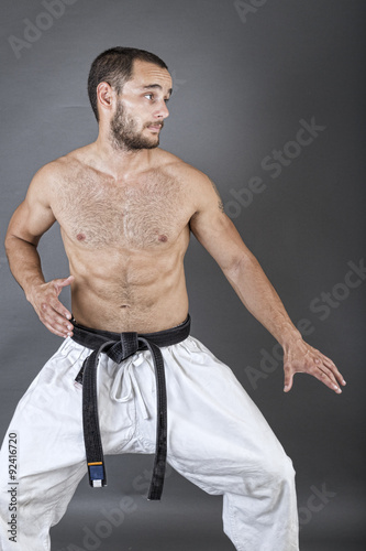 Portrait of young man in white kimono and black belt training ma © jinga80