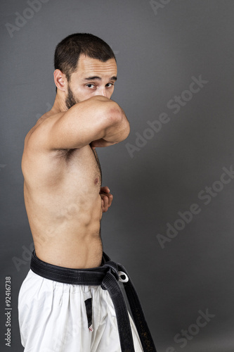 Portrait of young man in white kimono and black belt training ma © jinga80