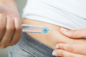 close up of hands making injection by insulin pen