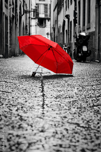 Fototapeta Red umbrella on cobblestone street in the old town. Wind and rain