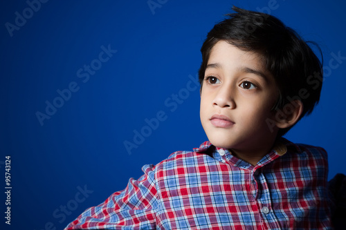 Little Asian kid posing in-front of a blue wall.