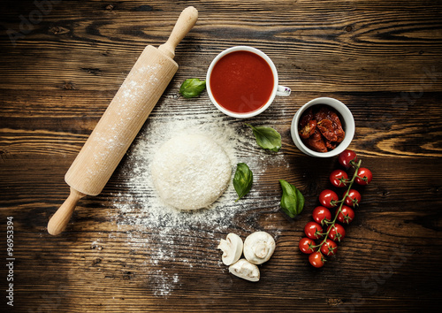 Poster Pizza dough with ingredients on wood
