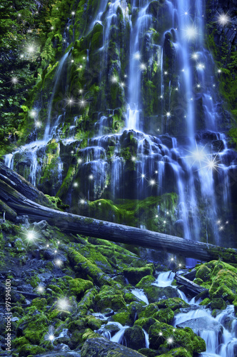 Fototapeta Waterfall with fairies and magical blue moonlight affect/Magical waterfall with fairies and blue misty water cascading over green mossy rocks