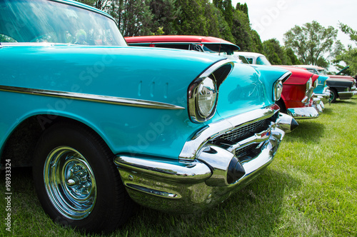 Vintage hot rods at a car show front ends. A row of awesome hot rods at a car show restored front ends with headlights exposed engines and grilles. Row of cars at a car show.