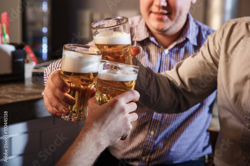 Zdjęcia Happy friends drinking beer at counter in pub