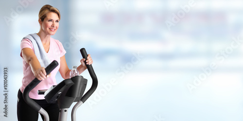 Mature woman doing exercise on elliptical trainer. © Kurhan