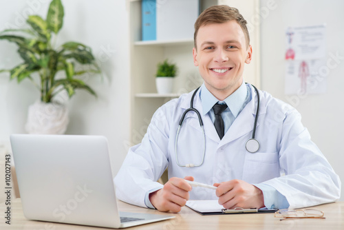 Zdjęcia Smiling pediatrician sitting at the table
