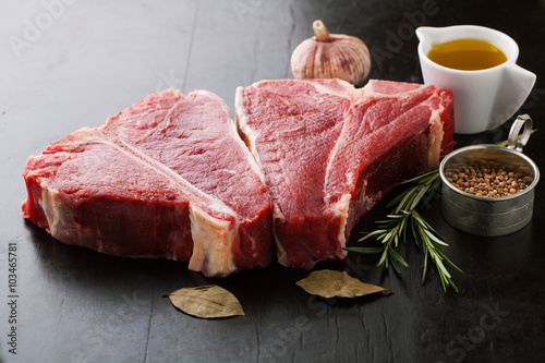 Raw meat t-bone steak with herbs, spices, garlic and rosemary