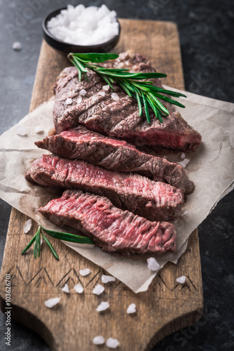 Zdjęcia Grilled beef steak with rosemary and salt on cutting board