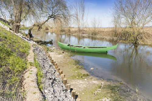 Poster green canoe parked in the shore of a river in Azinhaga, Santarém, Portugal