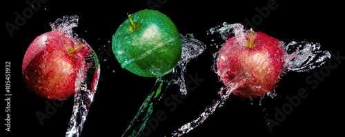  Three apples in water splashes over black background