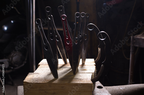 Poster throwing knives stuck into a wooden block with background light