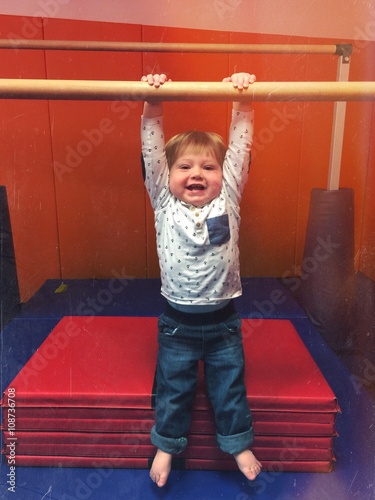 Baby In Gym On Gymnastic Bar Trying To Do Pullup And Is Hanging Baby In Gym On Gymnastic Bar Trying To Do Pullup And Is Hanging