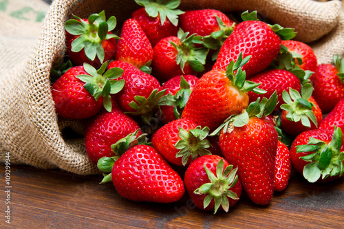 fresh strawberry in burlap sack on wood