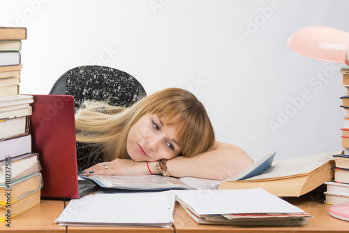 Poster Girl student laid her head on her hand crammed with books and papers lying on th