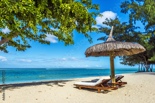 White sand beach with lounge chairs and umbrella in Mauritius Is