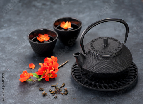 Black iron asian style teapot and cups green tea and flowers