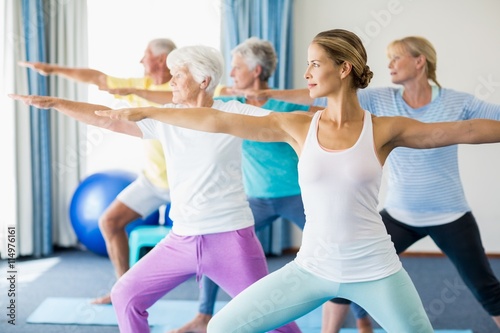 Zdjęcia Instructor performing yoga with seniors