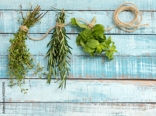  Thyme, rosemary and mint hanging on twine over blue wood