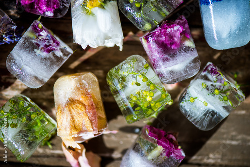 Frozen Flowers in Ice Cubes on Rustic Wooden Background