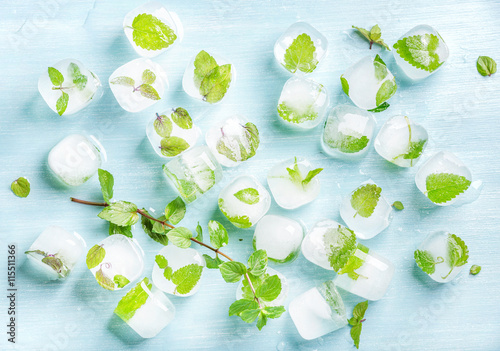 Ice cubes with frozen mint leaves inside on blue Turquoise background
