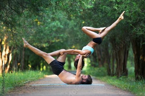 Zdjęcia Acro yoga, two sporty people practice yoga in pair, couple doing stretching exer