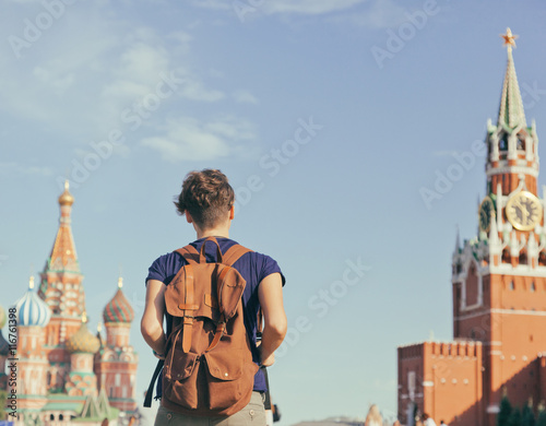 Poster Young attractive woman traveler with backpack on the background
