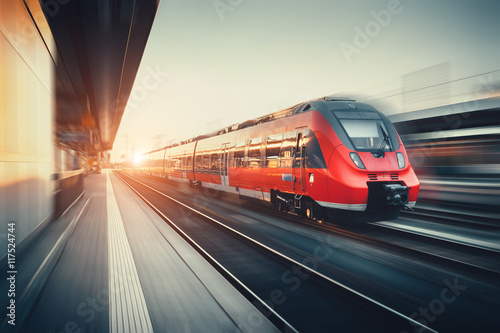 Poster Beautiful railway station with modern red commuter train at suns