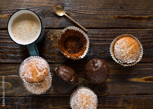 Poster Homemade vanilla and chocolate muffins with a cup of hot coffee on a dark wooden table