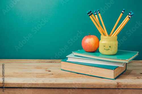 Poster Back to school concept with books, pencils in emoji jar and apple on wooden tabl