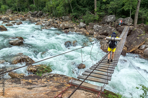 Poster Tourist passes on the suspension bridge over the Selenginka River