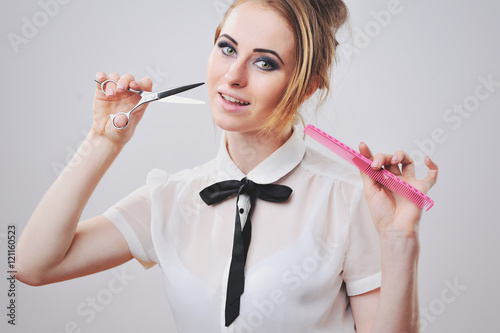 Poster girl with curly hair holding scissors and hair dryer isolated on white, backside