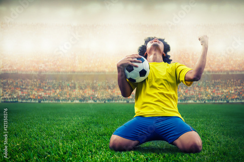 Poster soccer or football player celebrating goal in the stadium during match
