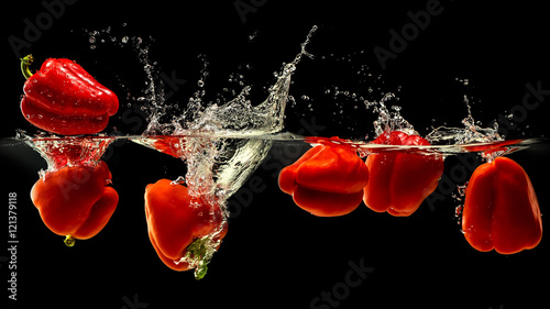  Group of bell pepper falling in water with splash on black background