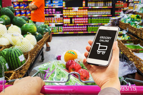 Smart phone with grocery shopping online on screen over blur supermarket background, retail business and technology concept