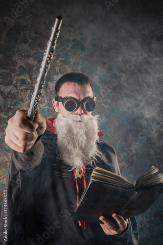 Poster evil wizard Merlin conjures and casts a spell, raising his wand, a young man dre