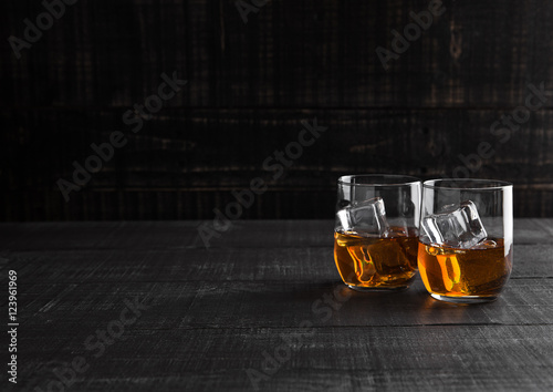 Glasses of whiskey with ice on wooden background